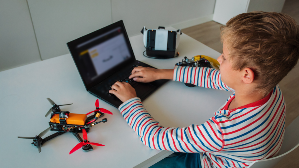 Boy sitting at a laptop programming a drone