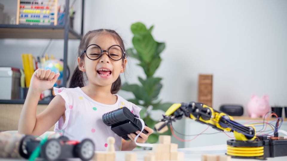 Young girl with a self-satisfied look as she controls a robotic arm
