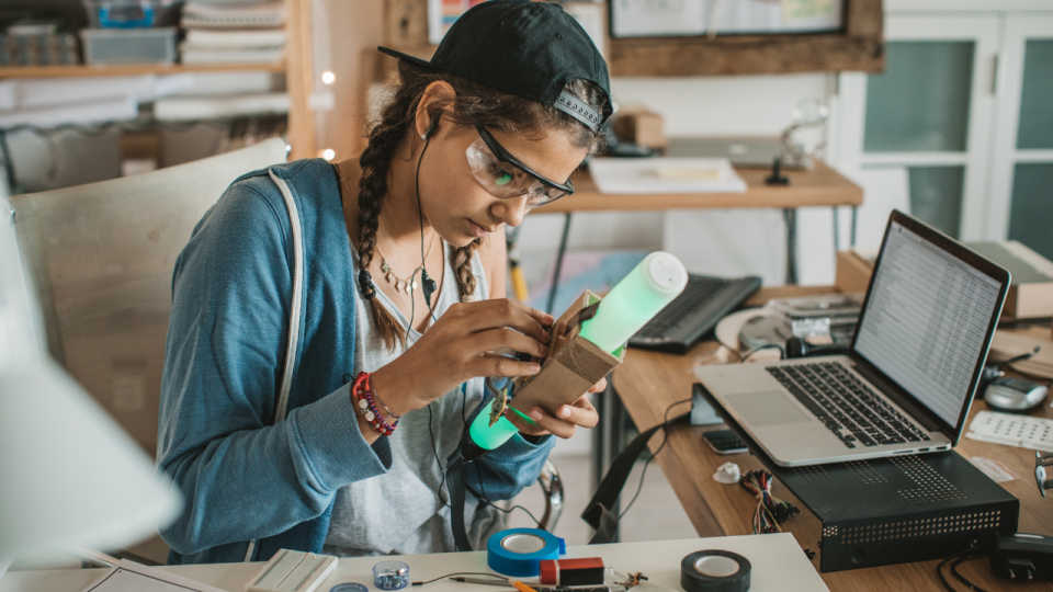 Teenage girl working on an electronics project involving a neon glow tube