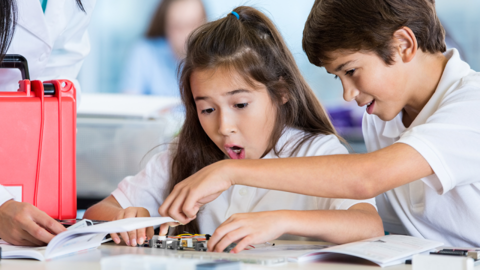 Very excited girl working with boy on electronics project