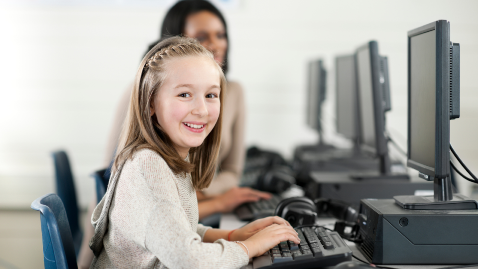 Smiling girl sitting at a computer in a computer lab