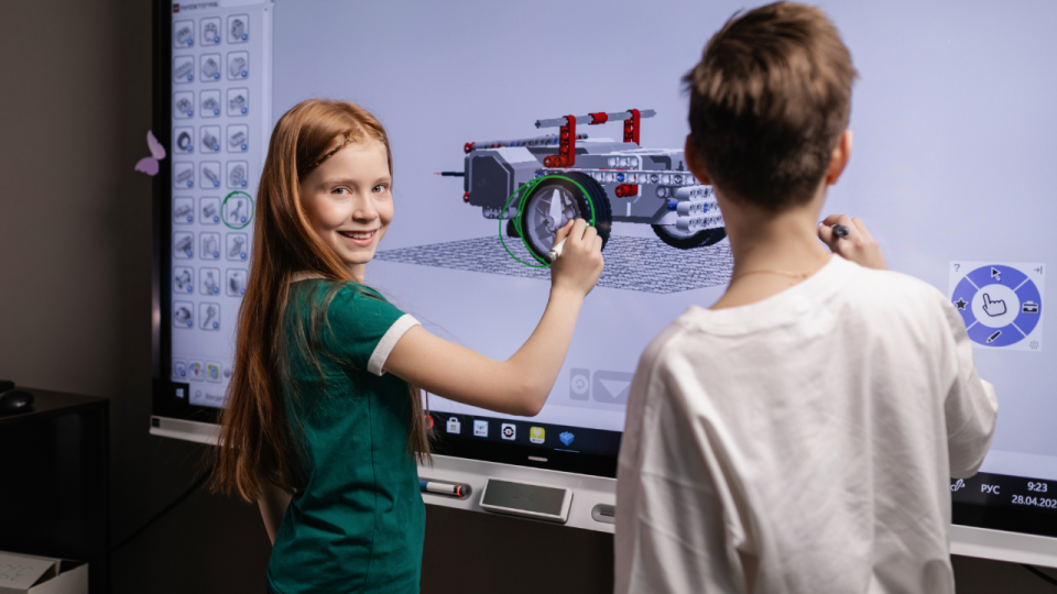 Girl and boy standing at a smartboard and working on a 3D model